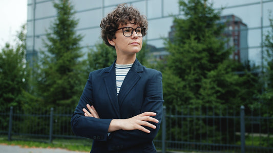 Woman with curly hair in a suit with arms crossed.