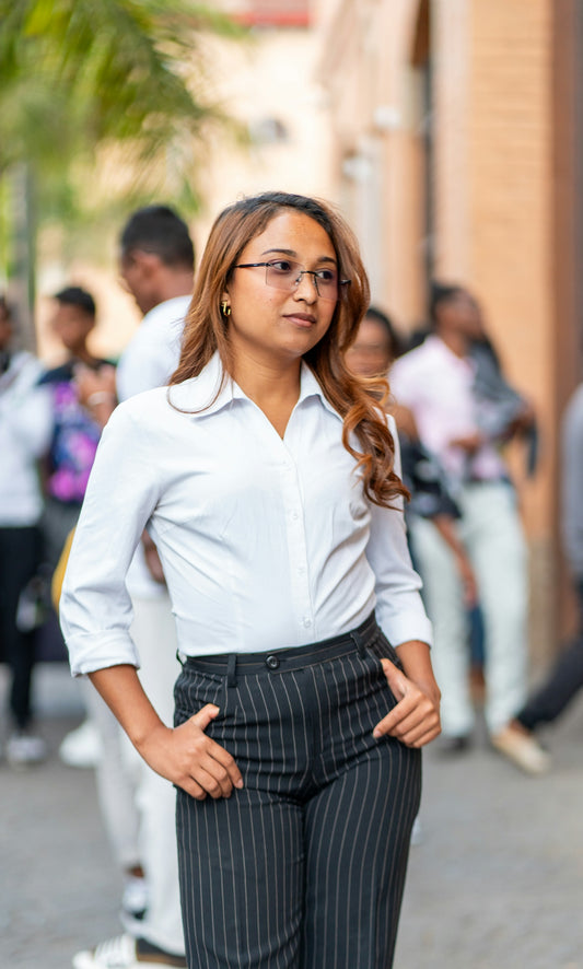 Young woman in glasses and pinstripe pants walks outside.