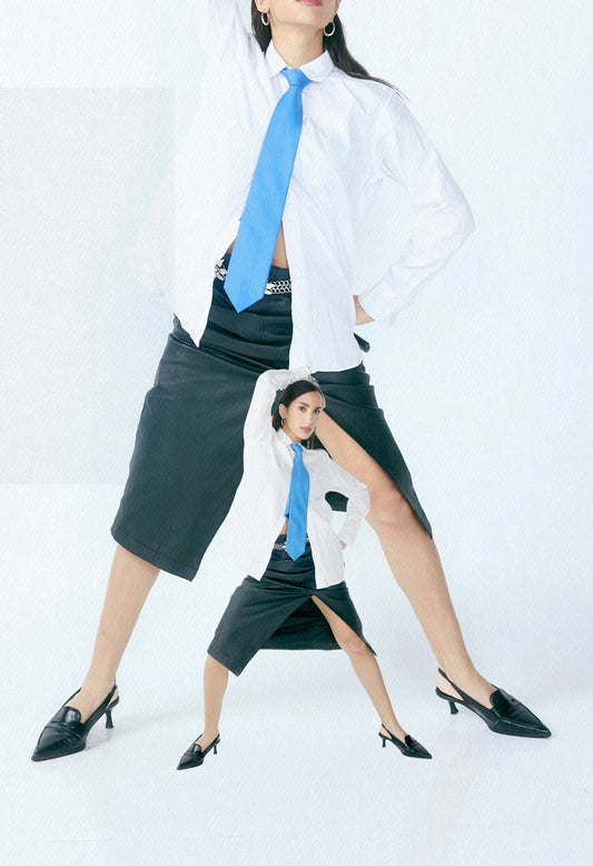 Woman in white shirt and blue tie poses dramatically.