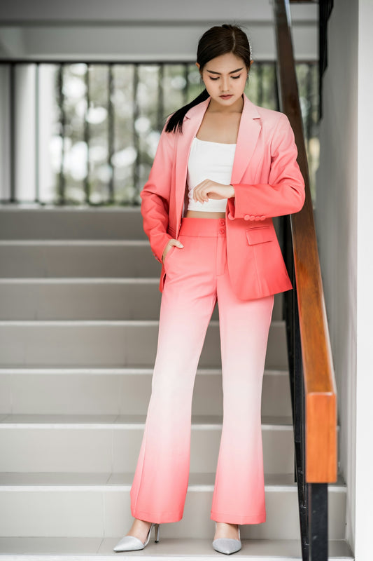 woman wearing pink and white ombre blazer and pants staring on her watch