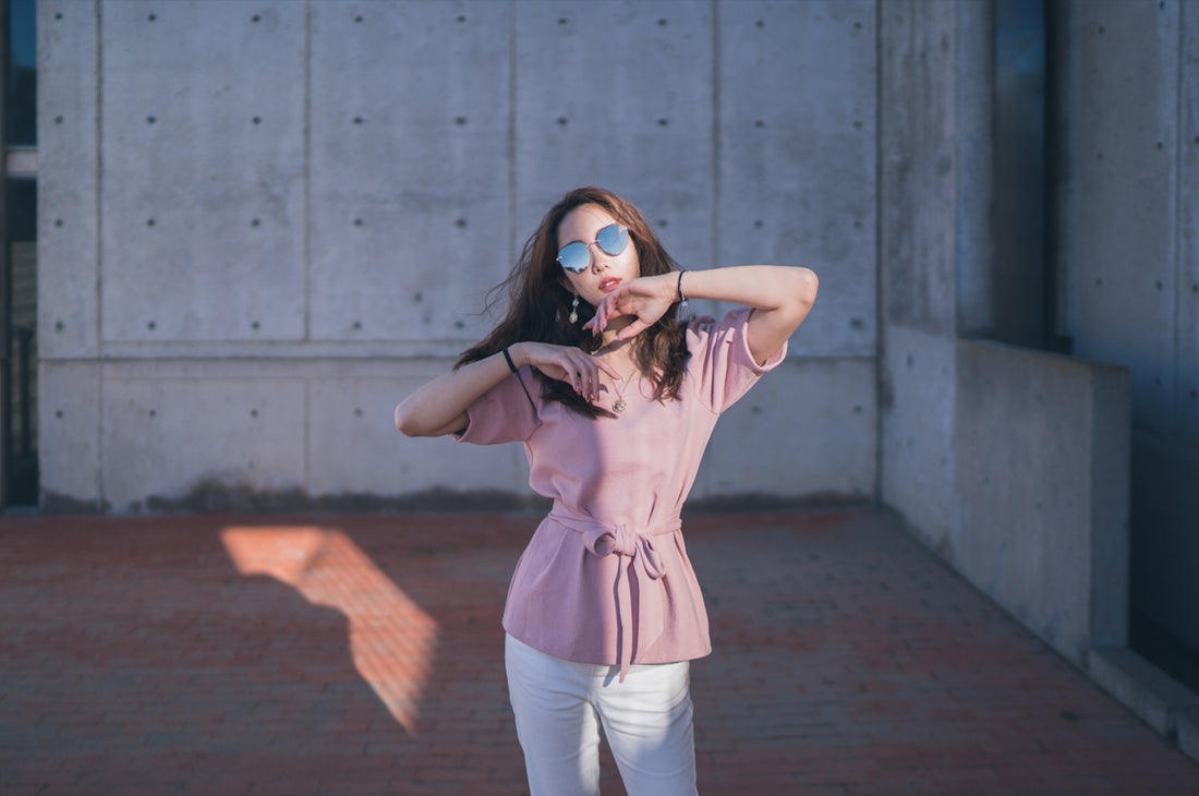 woman in pink sleeveless shirt and white pants standing on brown wooden floor
