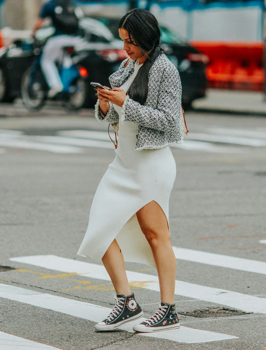 a woman walking across a street while looking at her cell phone