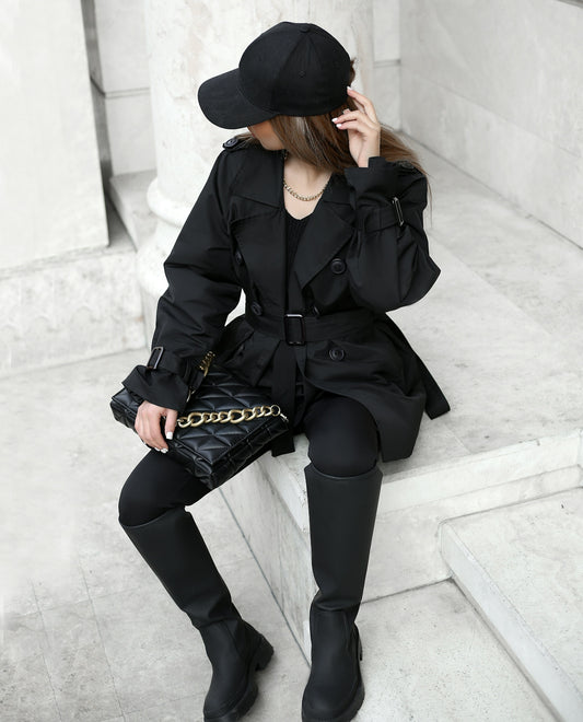 a woman in a black coat and hat sitting on steps