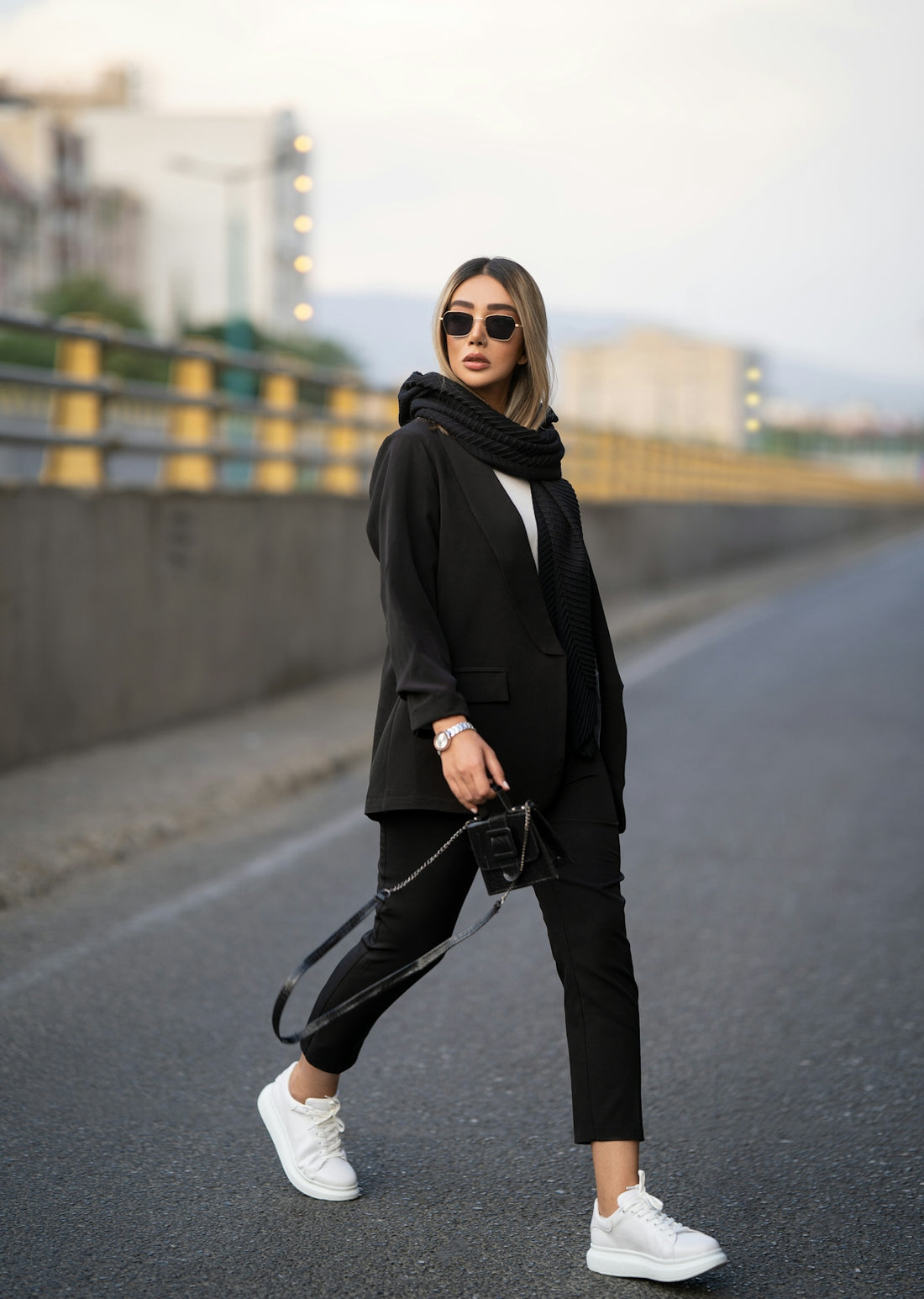a person in a black coat and sunglasses walking on a street