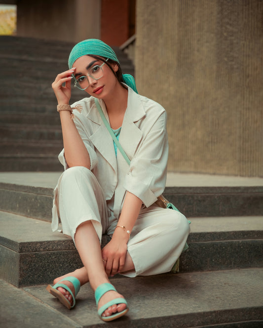 Woman in stylish outfit sits on stairs.