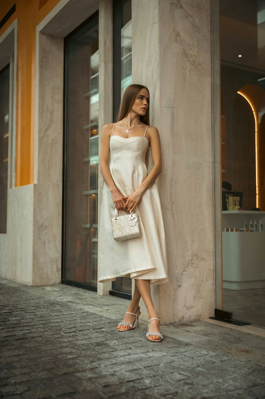 Woman in elegant dress poses outdoors.