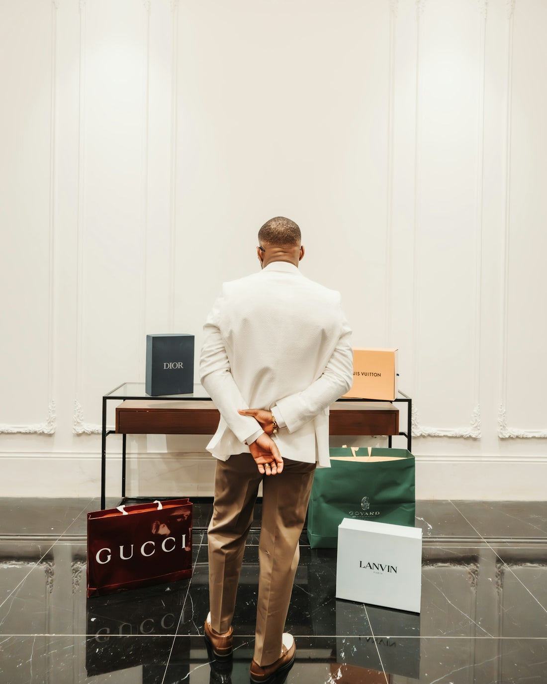 Man in white suit with luxury shopping bags