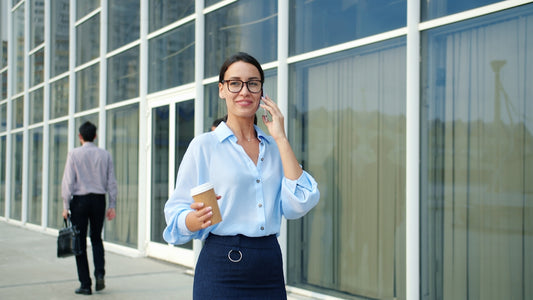 Woman talking on phone holding coffee cup outside office