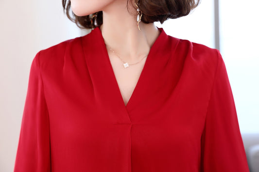 A woman in a red blouse with a necklace.